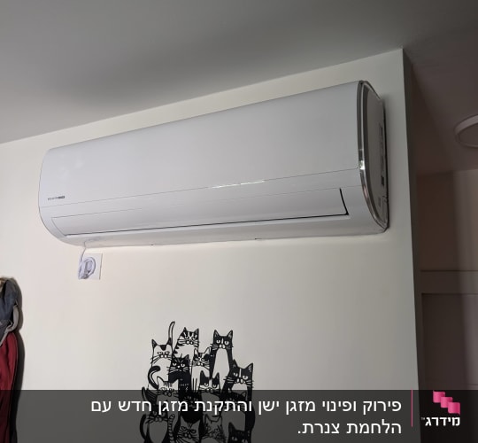 מזגן מותקן על קיר עם ציור של חתולים